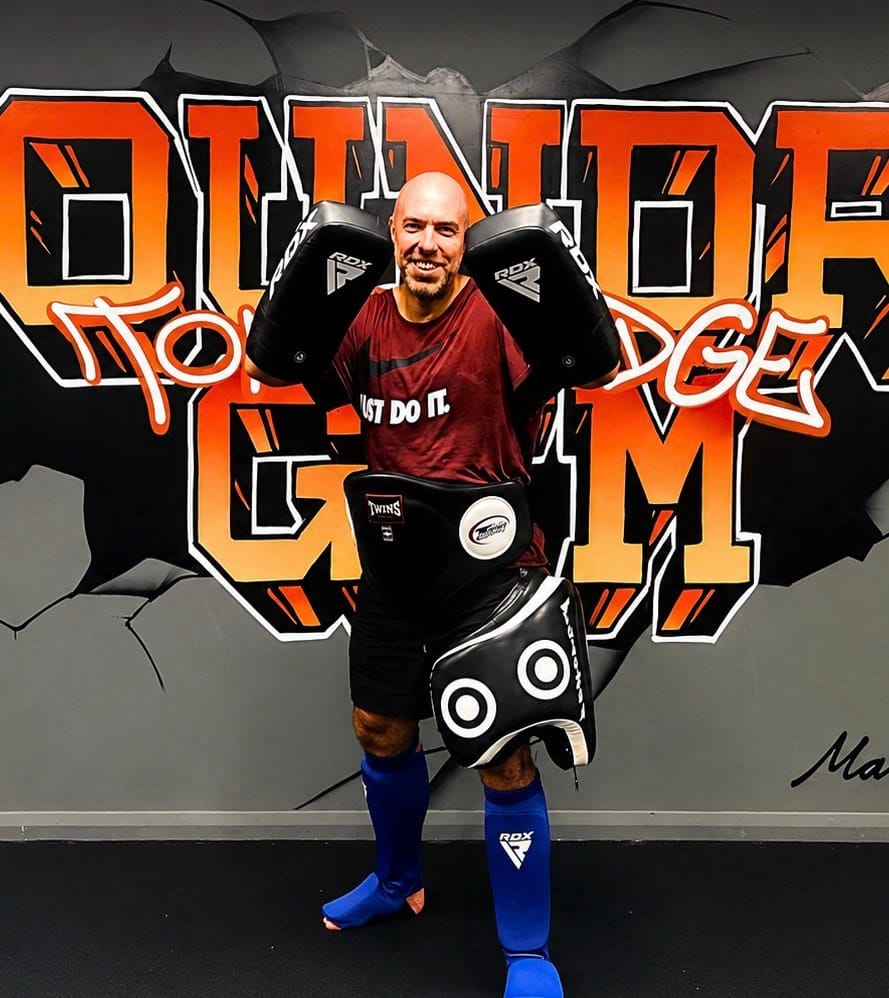 Danny Richards, Level 3 Personal Trainer, in Muay Thai kit with Thai pads and a belly pad